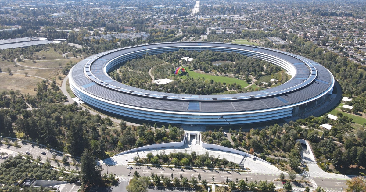 An aerial view of Apple Park in 2022, with its ring-shaped main building surrounded by gardens and trees